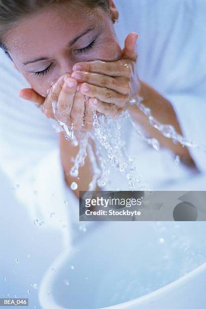 woman rinsing face with water from basin - basin ストックフォトと画像