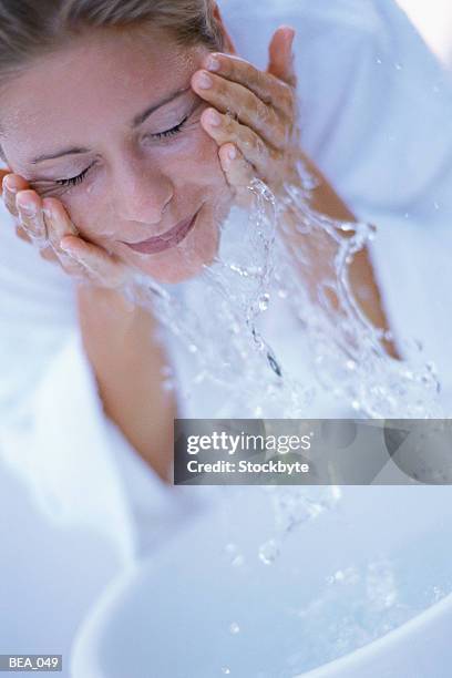 woman washing face with water from basin - basin ストックフォトと画像