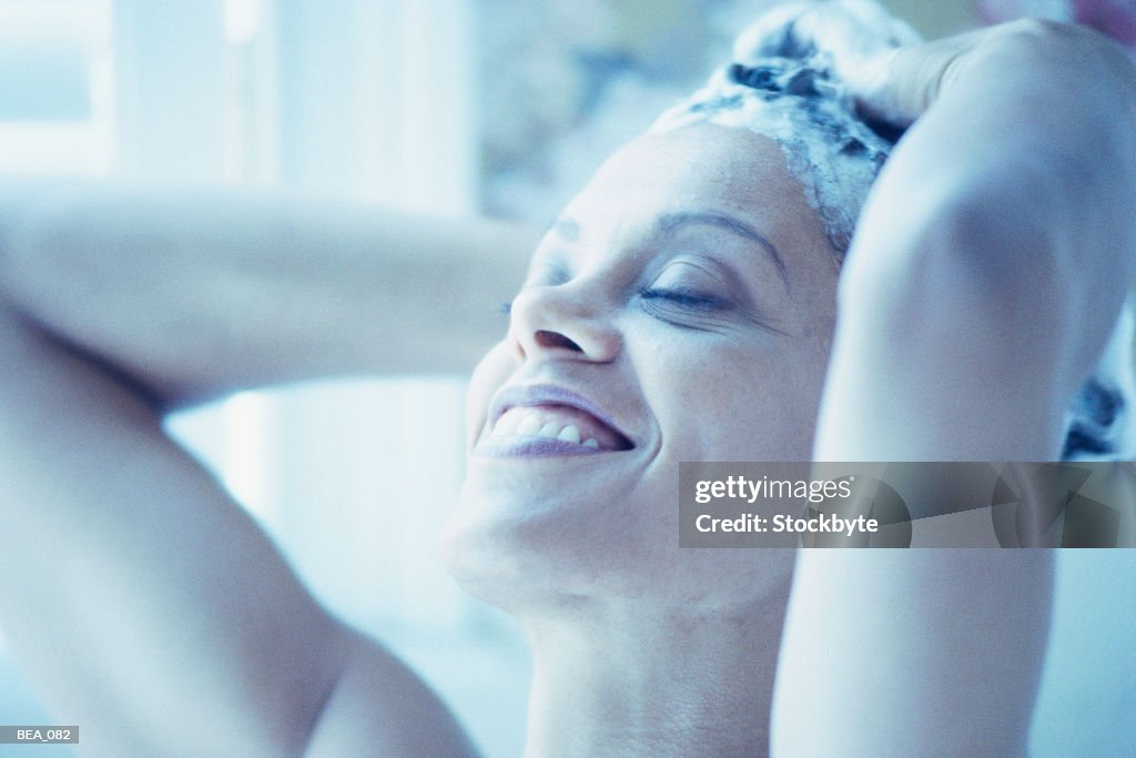 Woman shampooing hair and smiling