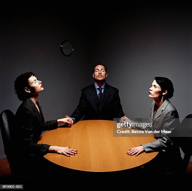 two businesswomen and businessman holding seance - séance photo stock pictures, royalty-free photos & images