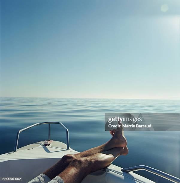 man resting legs on side of boat, close-up - feet up 個照片及圖片檔