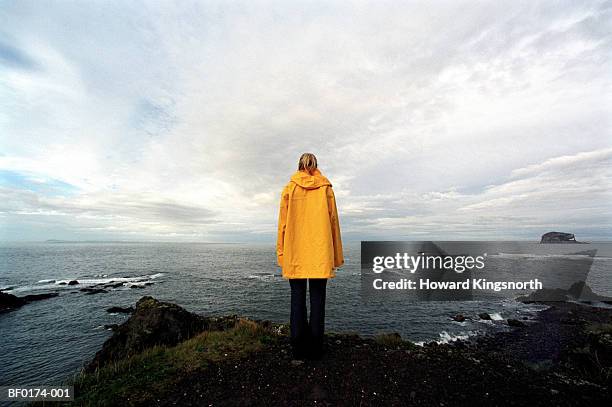 scotland, aberlady bay, woman wearing waterproof coat, rear view - レインコート ストックフォトと画像