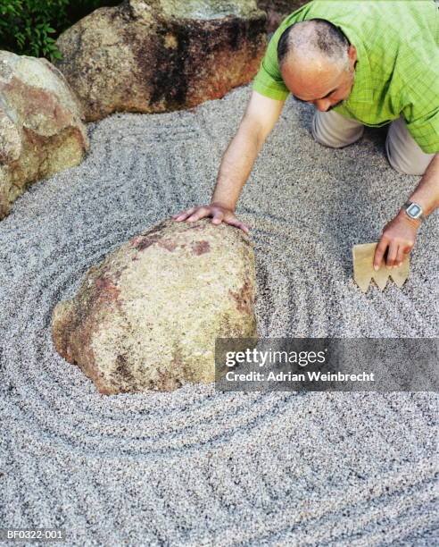 mature man working on zen rock garden, elevated view - karesansui stock-fotos und bilder