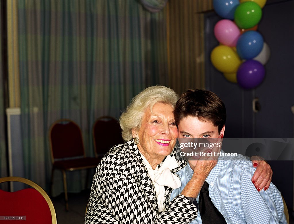 Elderly woman embracing teenage boy (13-15), portrait