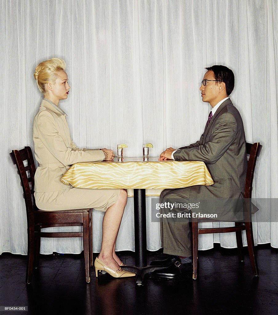 Young couple sitting at table, face to face