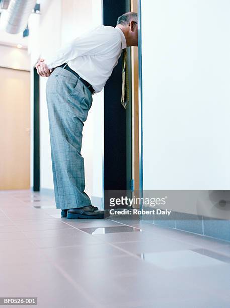 mature businessman looking into doorway - eavesdropping stock pictures, royalty-free photos & images