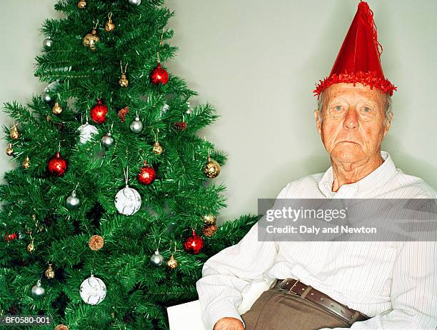 elderly man beside christmas tree, portrait - grumpy man stock pictures, royalty-free photos & images