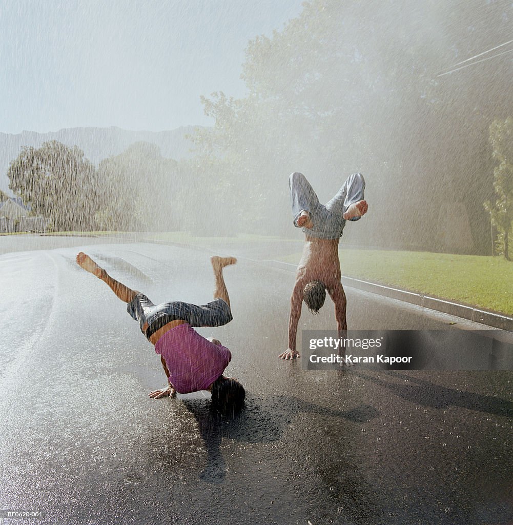 Two young men doing handstands in rain