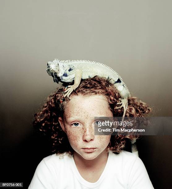 girl (7-9) with iguana on head - kriechtier stock-fotos und bilder