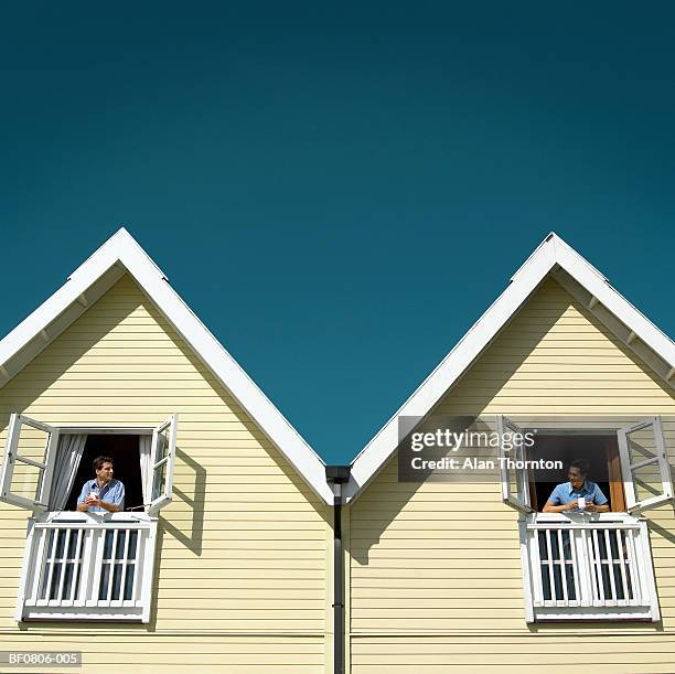 two men leaning out of adjoining chalet windows (digital composite) - neighbours talking stock pictures, royalty-free photos & images