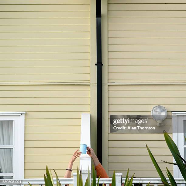 man passing cup to woman over fence - buren stockfoto's en -beelden