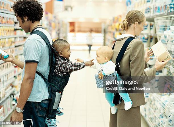 baby boy and girl (9-15 months) in baby carriers, pointing, profile - baby pointing stockfoto's en -beelden