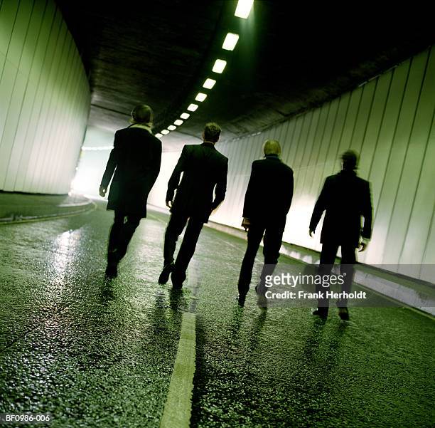 four men walking through tunnel towards exit, rear view - organized crime stock-fotos und bilder