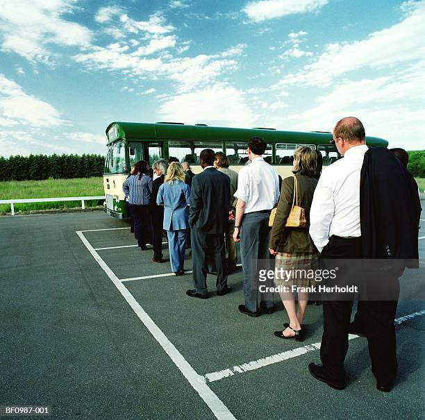 queue of people waiting to board bus in car park, rear view - 人の列 ストックフォトと画像