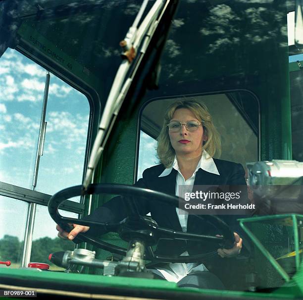 female bus driver at wheel, view through windscreen, portrait - autista di autobus foto e immagini stock