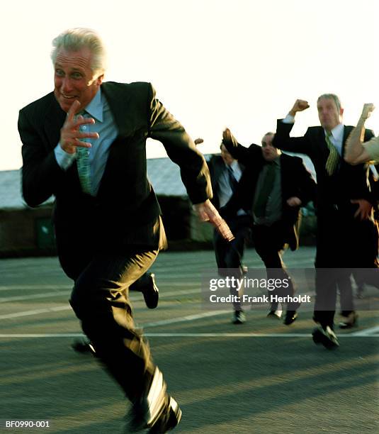 mature businessman running from crowd outdoors (blurred motion) - people escaping stock pictures, royalty-free photos & images