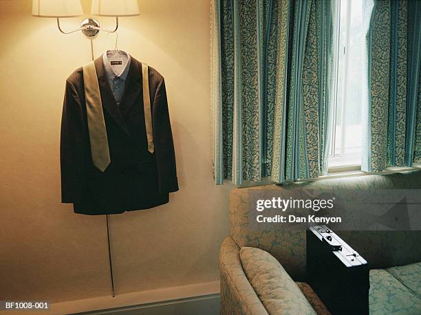 suit and tie hanging on light fitting beside briefcase on sofa - suits hanging stock pictures, royalty-free photos & images