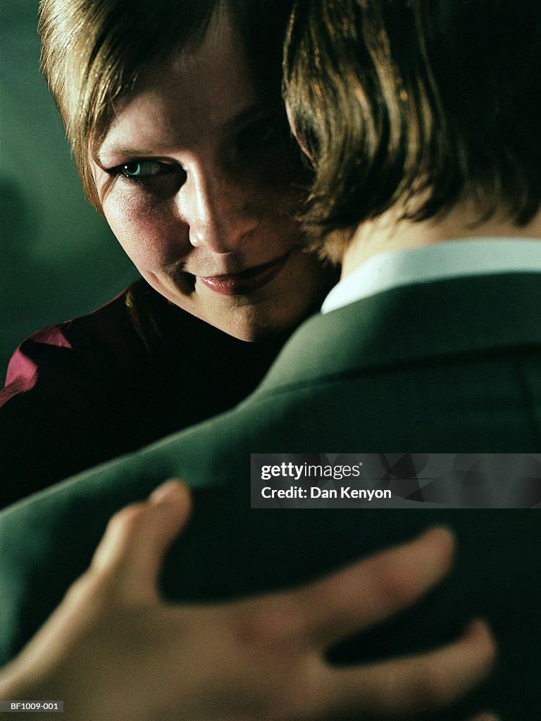 Young couple embracing, view over man's shoulder