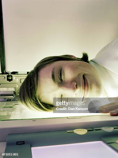 young male executive resting head on photocopier plate, close-up - photocopier stockfoto's en -beelden