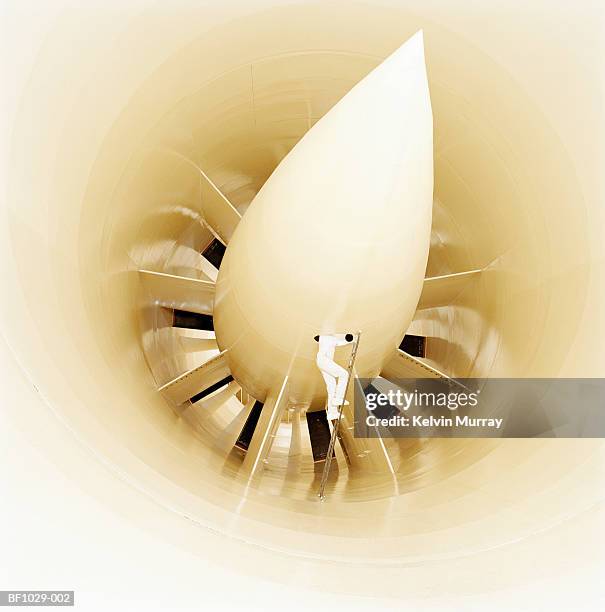man in overalls on ladder examining wind tunnel, low section - windkanal stock-fotos und bilder