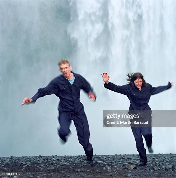 young couple running away from waterfall (blurred motion) - 逃げる ストックフォトと画像