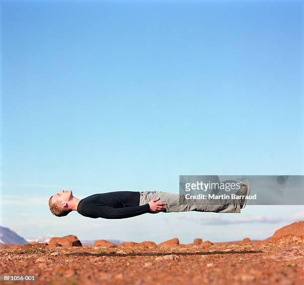 young man 'levitating' in desert, profile - lying down stockfoto's en -beelden