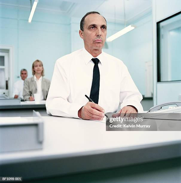 row of executives at desks, focus on man in foreground, close-up - trabalho fastidioso - fotografias e filmes do acervo