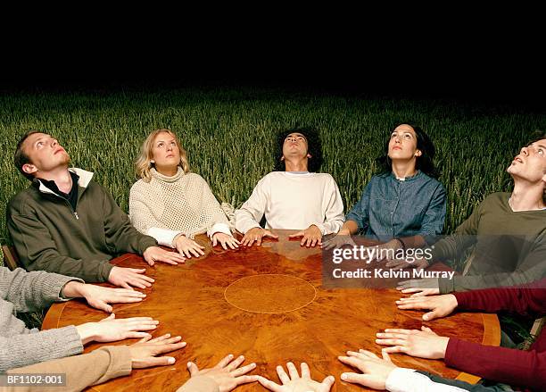 groups of friends performing seance around table in field, looking up - seduta spiritica foto e immagini stock