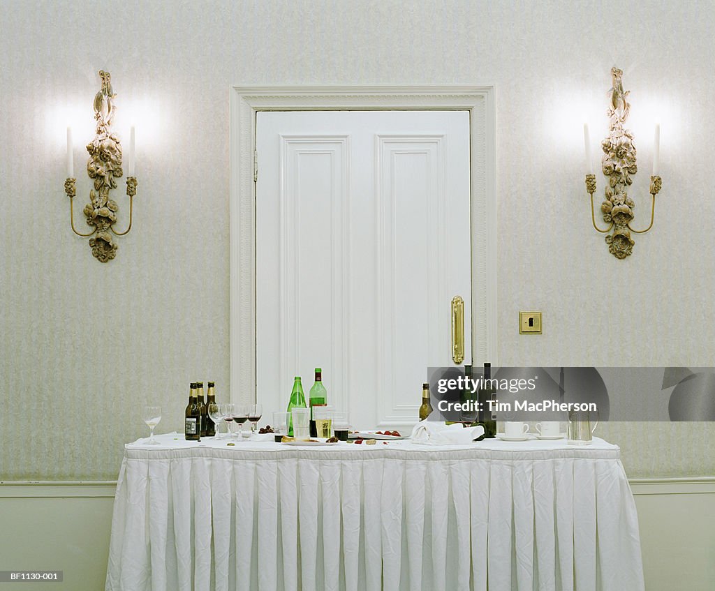 Bottles, half empty glasses and discarded food on buffet table