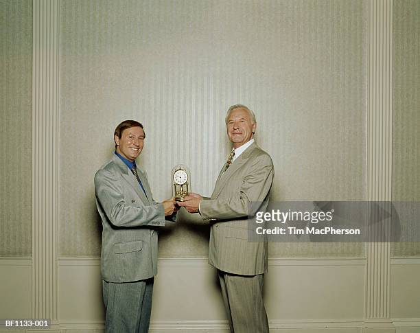 mature businessman receiving clock from male colleague, portrait - business awards ceremony stock pictures, royalty-free photos & images