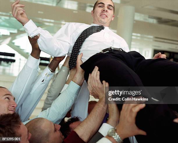 colleagues lifting up businessman, close-up - crowdsurfing stockfoto's en -beelden