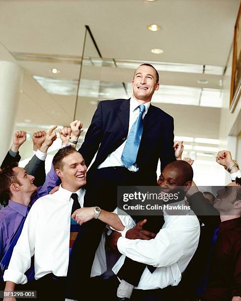 colleagues holding up and congratulating businessman - crowd surfing stock pictures, royalty-free photos & images