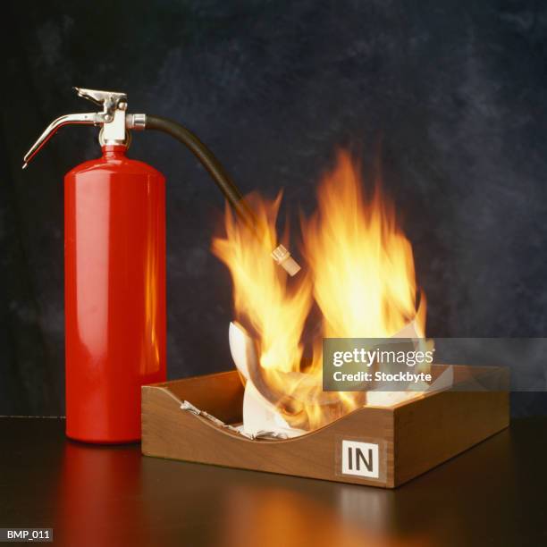 fire extinguisher beside office tray containing burning paper - emergency services equipment stock pictures, royalty-free photos & images