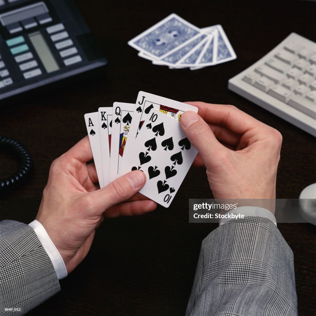 Man holding playing cards sitting at desk