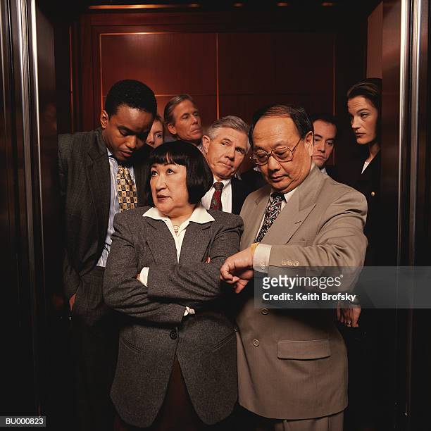 impatient businesspeople in a crowded elevator - business people group brown stock pictures, royalty-free photos & images