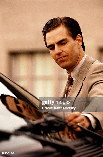 businessman reaching for citation on car - infrações de estacionamento - fotografias e filmes do acervo