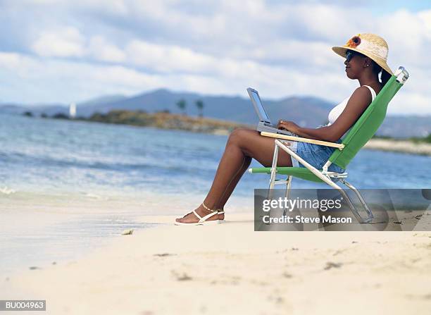 woman using a laptop on the beach - african creative with laptop working outside stockfoto's en -beelden