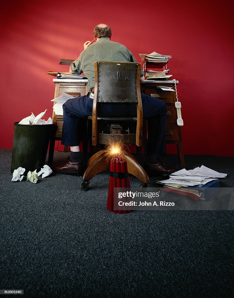Dynamite Behind Businessman at Desk