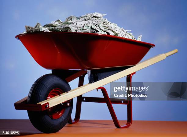 wheelbarrow full of money - money in wheelbarrow stockfoto's en -beelden