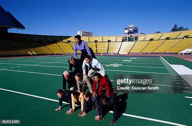 businesspeople building a human pyramid - human-pyramid stock pictures, royalty-free photos & images