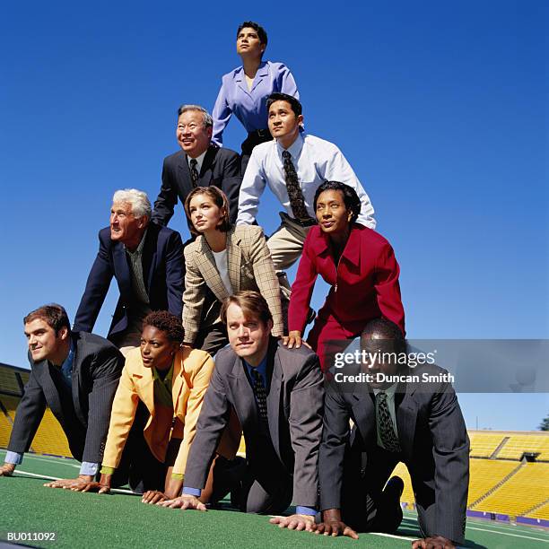 businesspeople building a human pyramid - human pyramid stock pictures, royalty-free photos & images