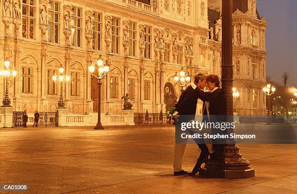 france, paris, couple embracing by lamp post outside hotel de ville - rathaus von paris stock-fotos und bilder