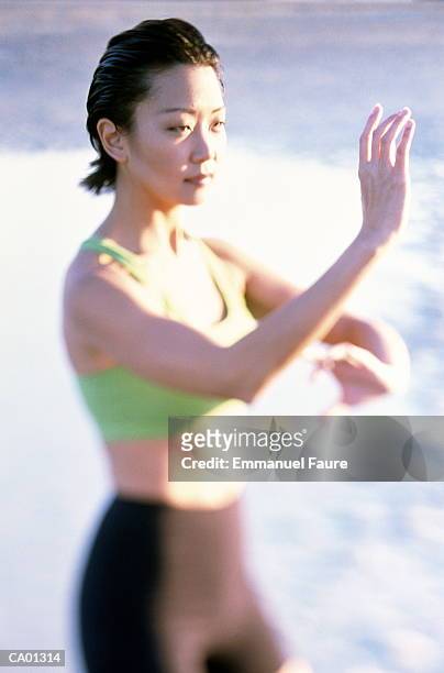 young woman practicing tai chi on beach (focus on face) - tai stock pictures, royalty-free photos & images