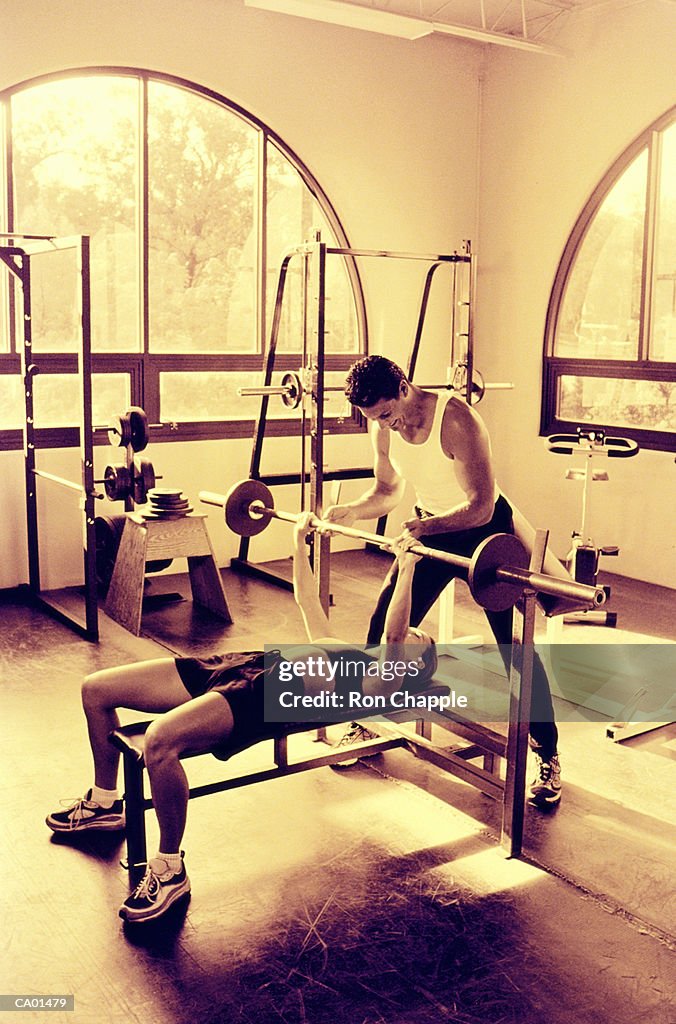 Man spotting woman doing bench press in gym (Toned B&W)