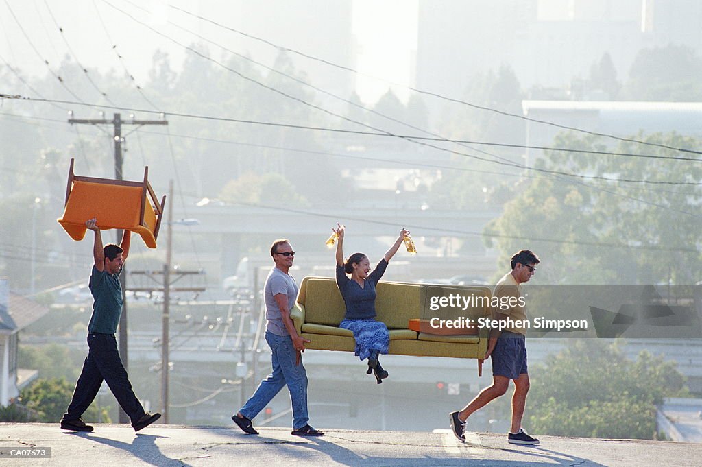 HISPANIC/AMER FRIENDS MOVING SOFA,WOMAN ON SOFA WITH BEER