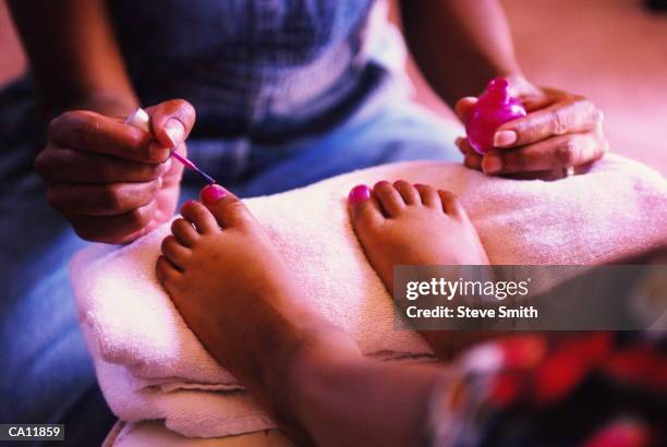 mother painting daughter's (7-9) toenails, close-up (gel effect) - black painted toes stock-fotos und bilder