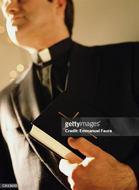 priest holding bible, close-up, low angle view - priest stockfoto's en -beelden