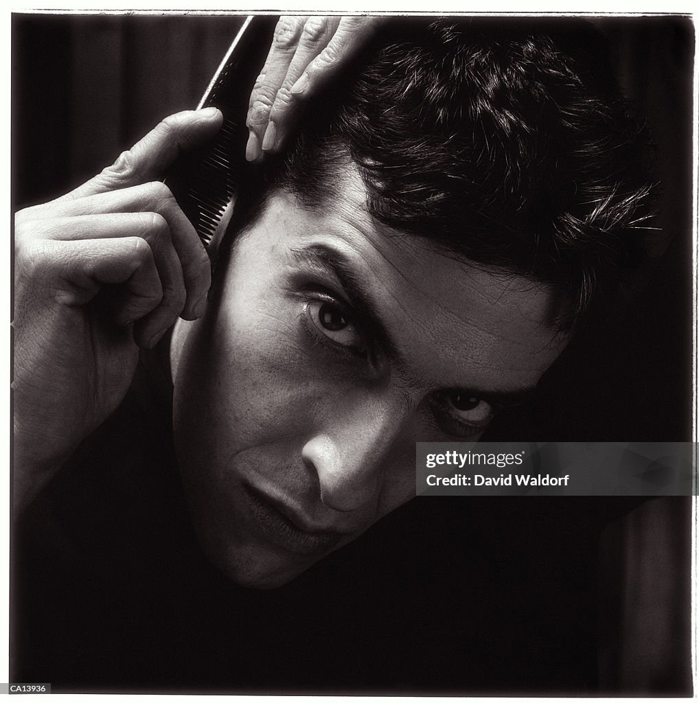 Man combing hair, portrait, close-up (B&W)