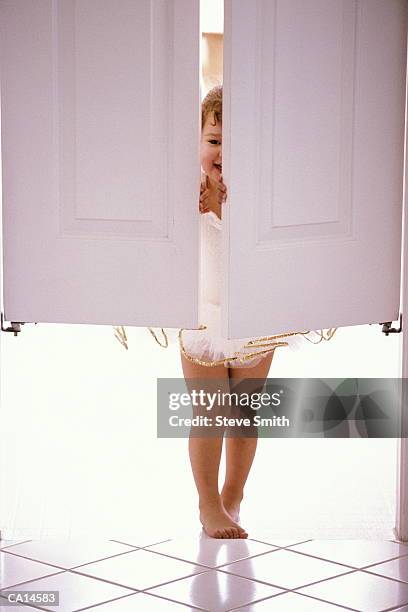 girl (2-4) wearing angel's costume, peeking through swinging doors - girl with legs open stock pictures, royalty-free photos & images