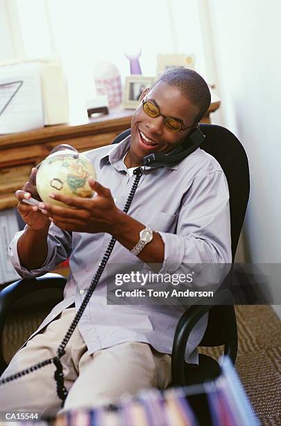 businessman talking on phone, holding globe - schreibtischspielzeug stock-fotos und bilder